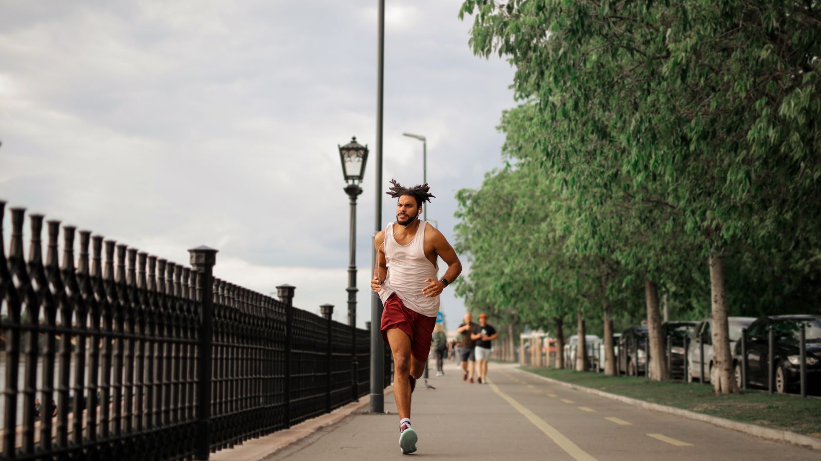 A man jogging on a tree-lined street