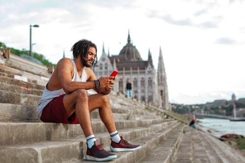 Man Using His Cellphone Sitting on Concrete Stairs