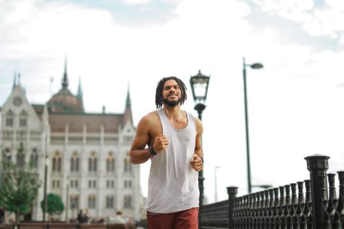 Free A man jogging outdoors near a grand historic building with a cathedral-style architecture. Stock Photo