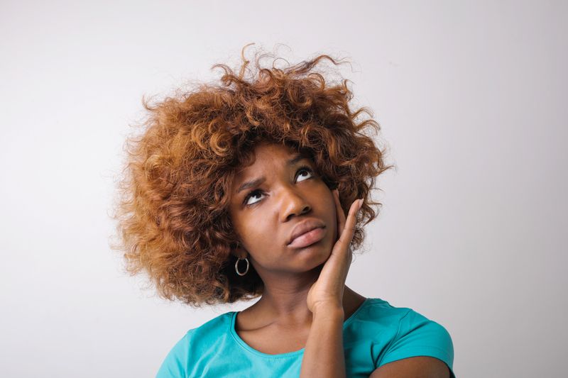 A young Black woman rests her hand against her cheek and looks away, deep in thought. Eating disorders in Black women are frequently overlooked because clinicians are less likely to ask about food, weight, or eating behavior.