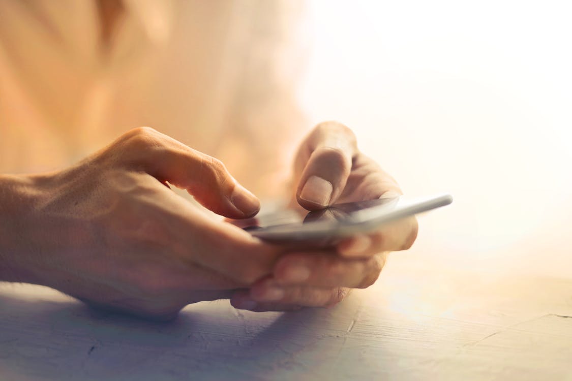 Person Holding White cell phone on White Table