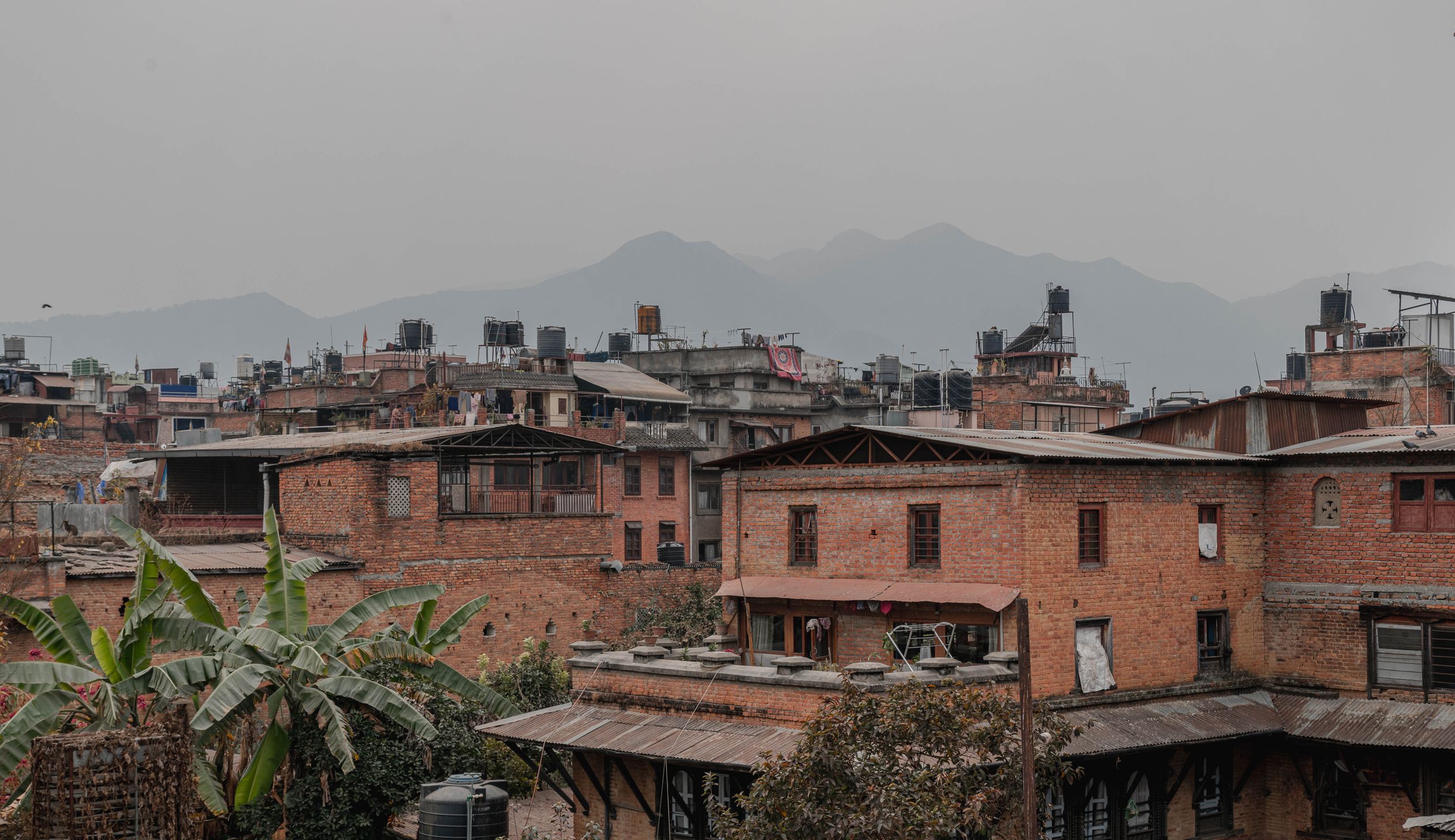 Charming view of Kathmandu's brick buildings with Himalayan backdrop, showcasing urban life.