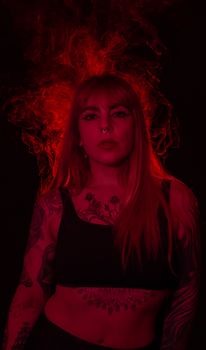 A powerful portrait of a tattooed woman under dramatic red lighting, evoking intensity.