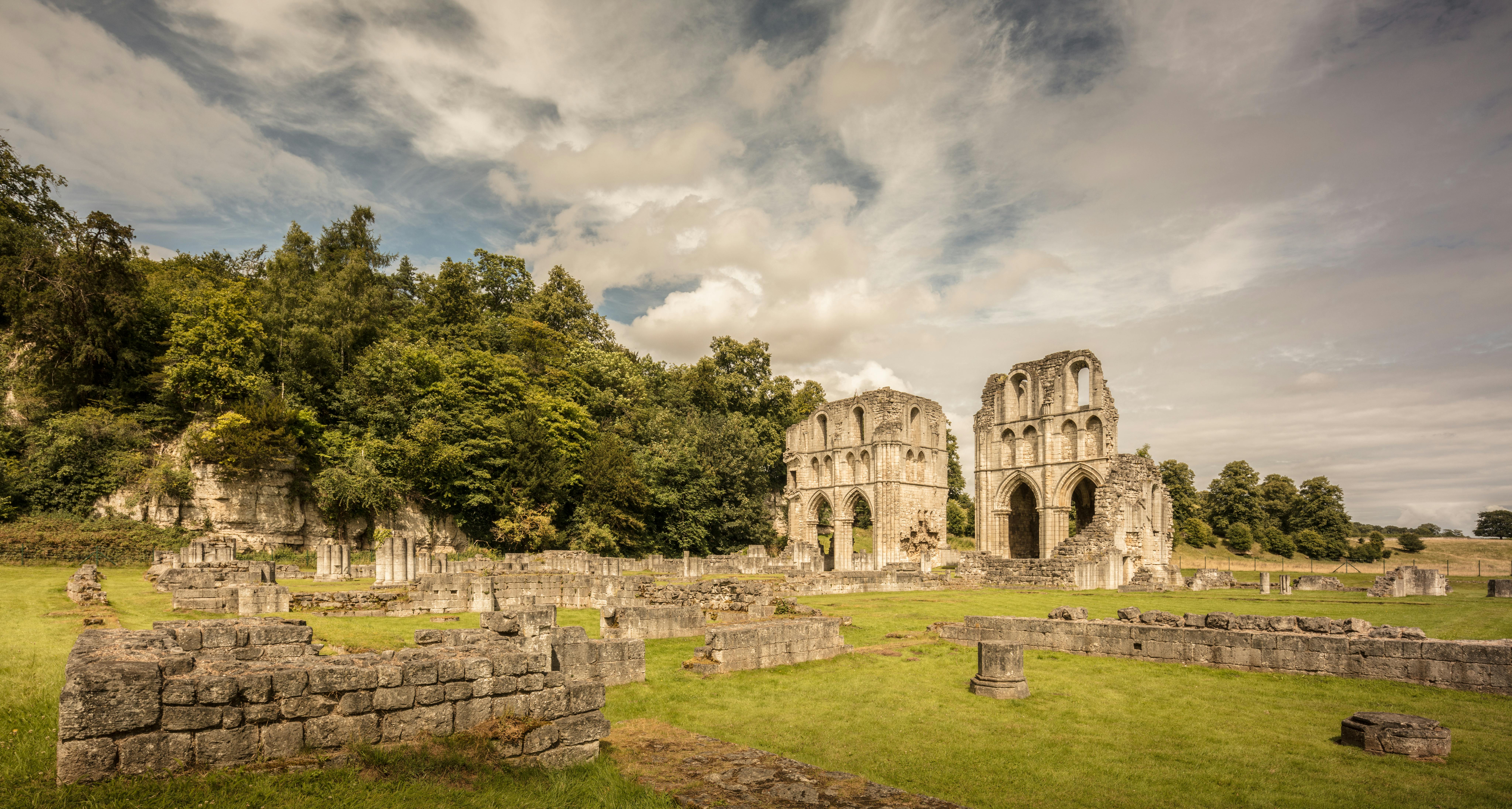 Explore the ancient ruins of Roche Abbey surrounded by lush greenery in Yorkshire, England.