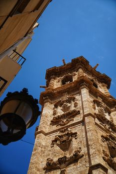 Stunning upward view of a baroque bell tower against a clear Valencia sky.