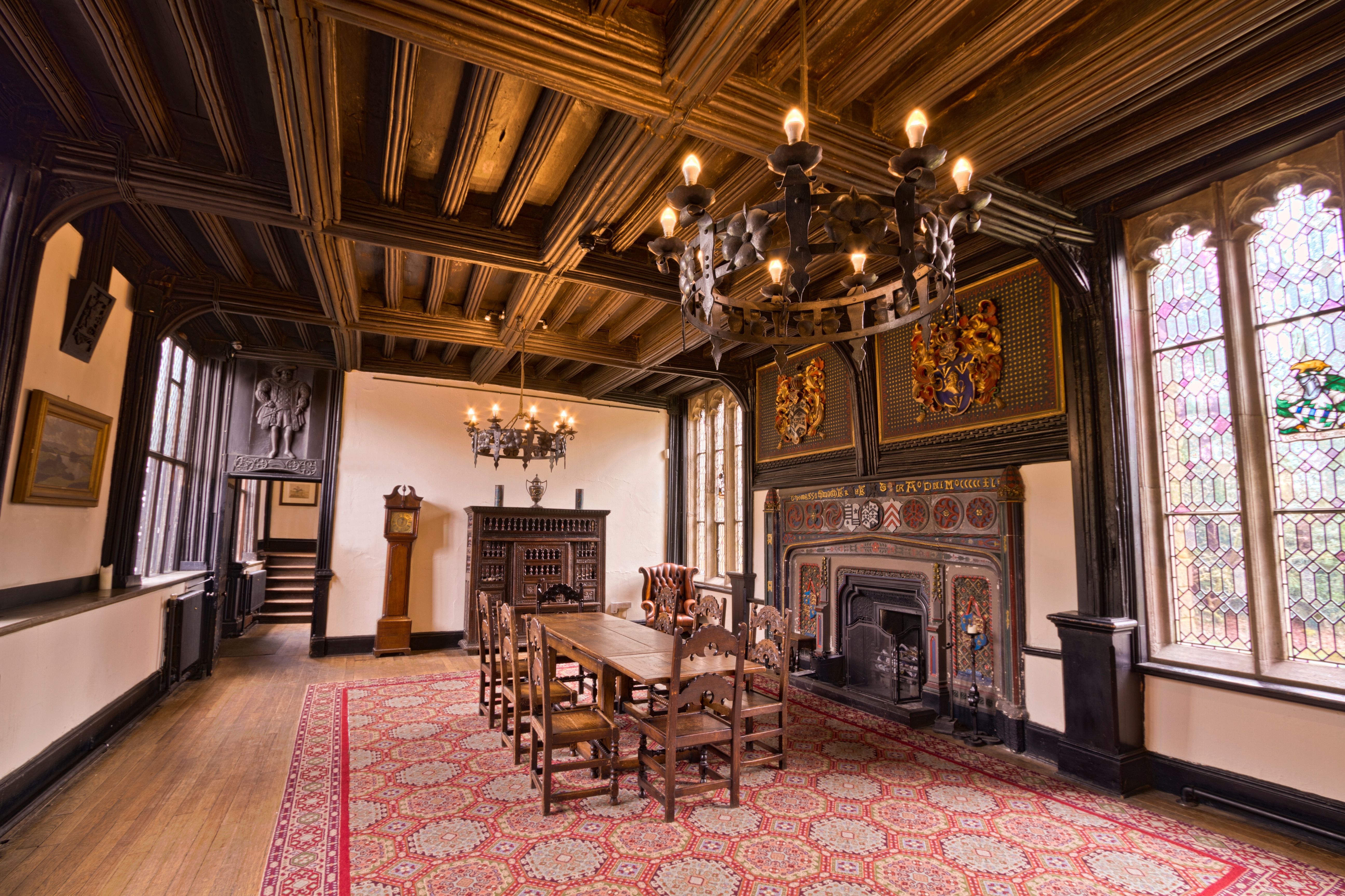 Elegant interior view of Samlesbury Hall featuring chandeliers, stained glass, and ornate woodwork.