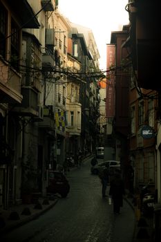 A narrow street in Istanbul's historic district at daytime, showcasing vibrant urban life and architecture.