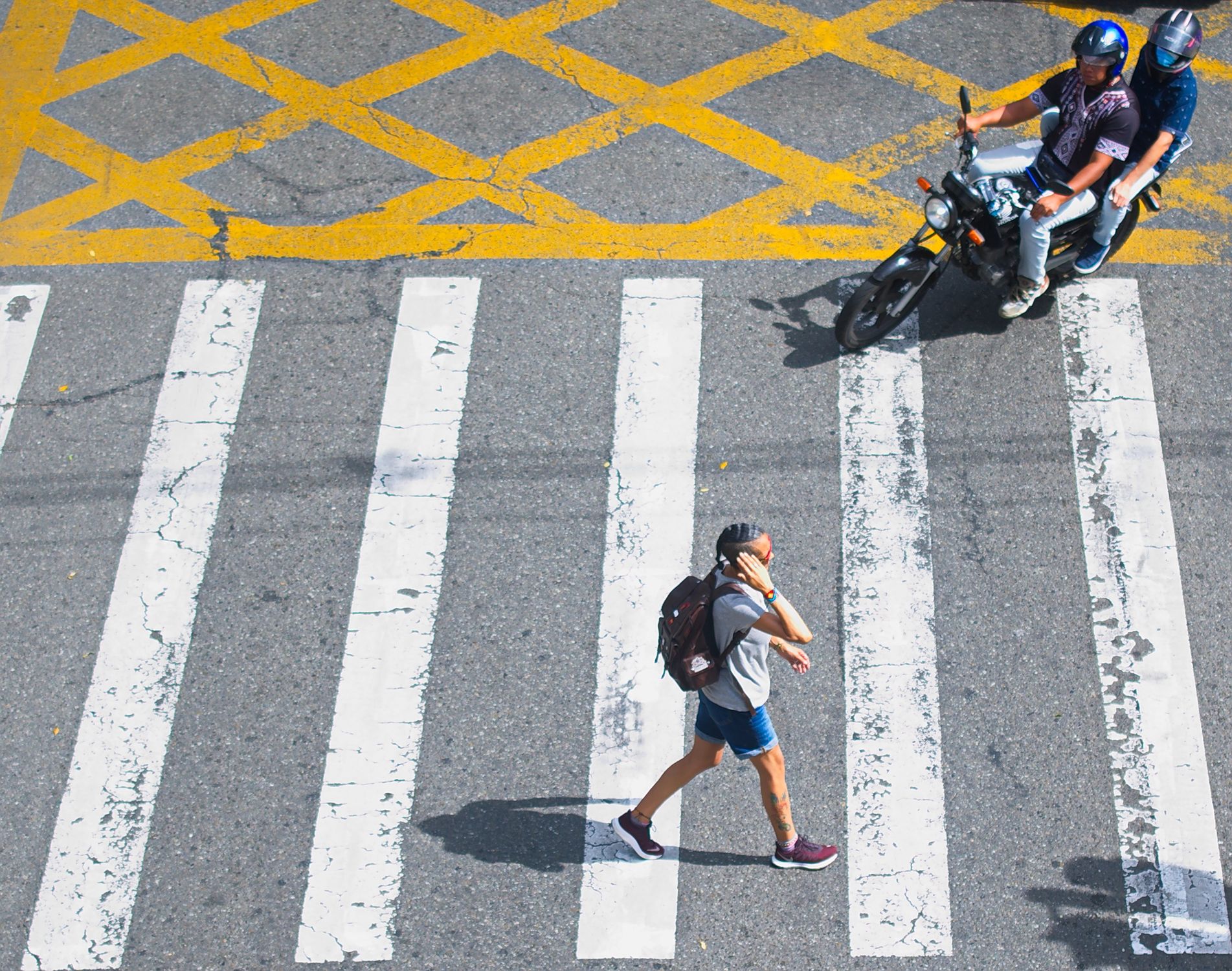 Aerial view of a pedestrian crossing a street with a motorcycle in Medellin, Colombia