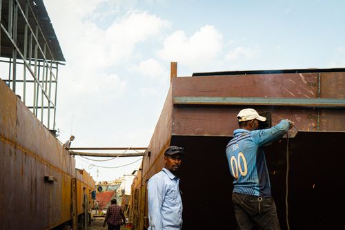 Free Two workers engaged in welding at a shipyard on a sunny day. Stock Photo