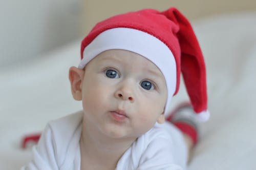 Free Baby Wearing Red Christmas Hat on White Textile Stock Photo