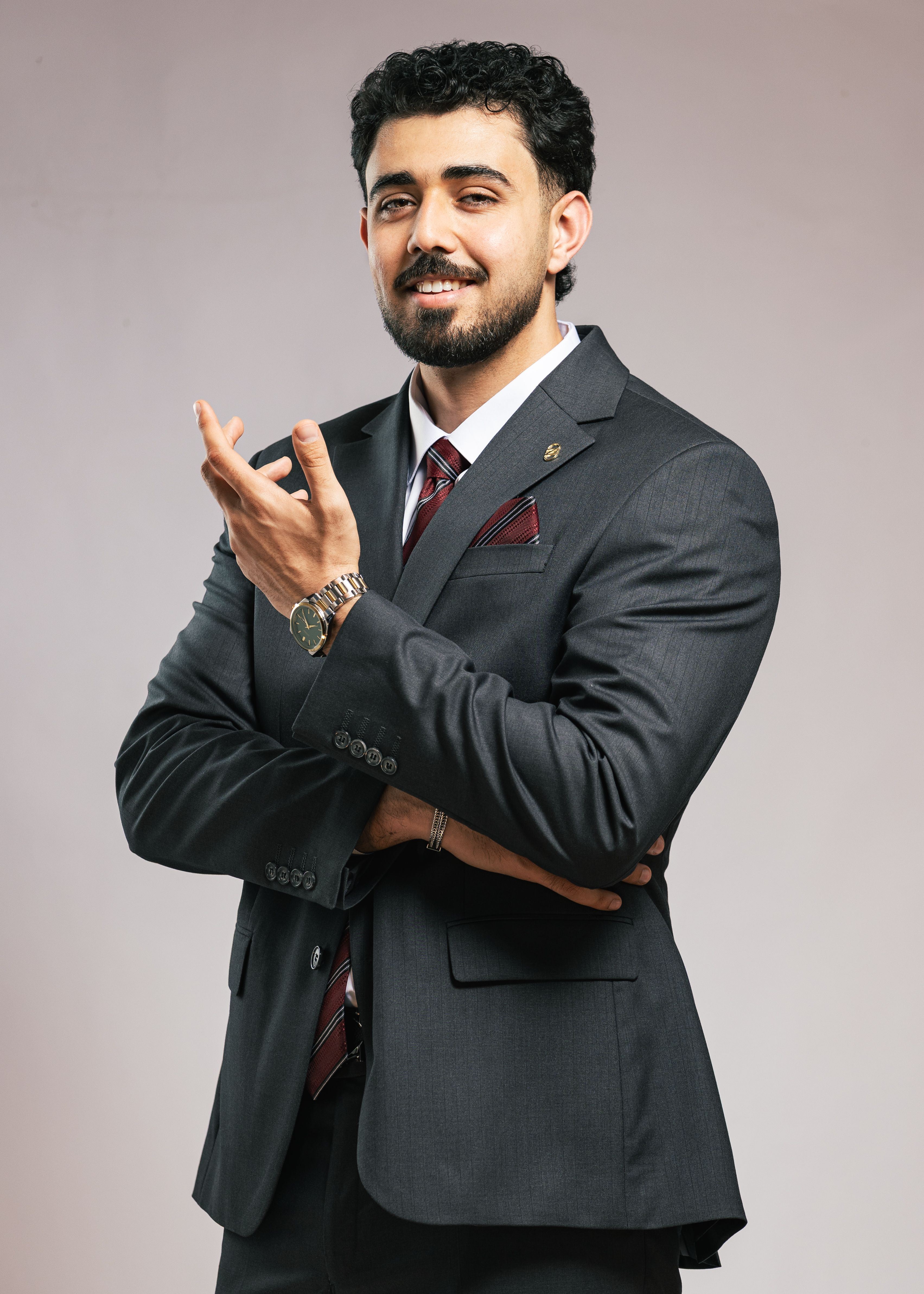 Professional man in formal suit confidently smiling with arms crossed.
