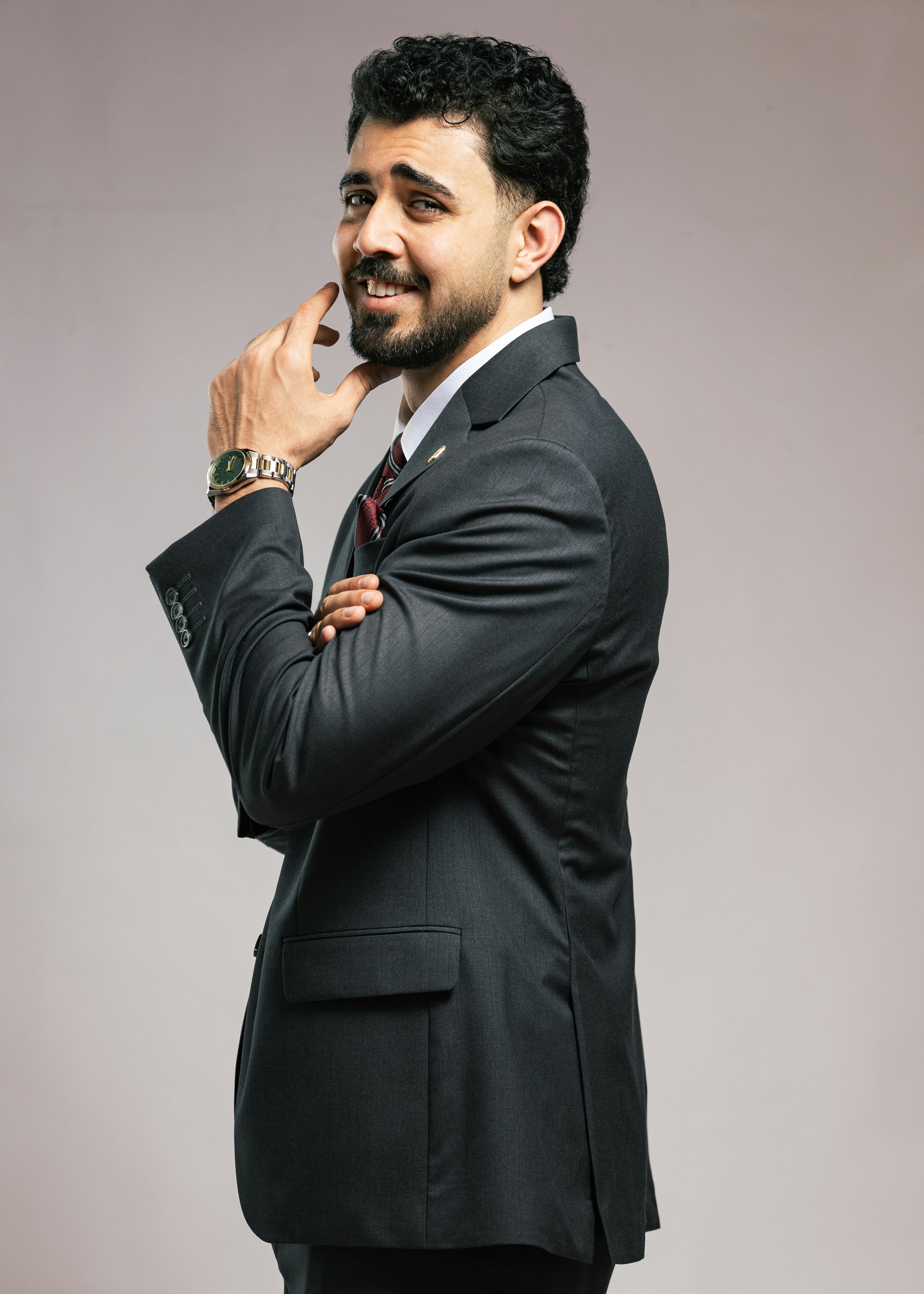 Portrait of a confident businessman in a black suit, striking a thoughtful pose.