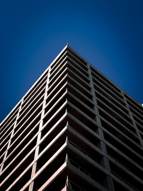 Free A striking perspective of a modern high-rise building with clear blue skies, showcasing urban architecture. Stock Photo