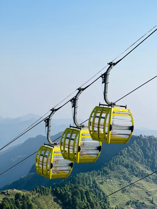 Free Vibrant yellow cable cars suspended above scenic mountains with lush greenery below. Stock Photo