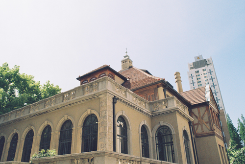 Free A classic building juxtaposes modern skyscraper under clear blue sky. Stock Photo
