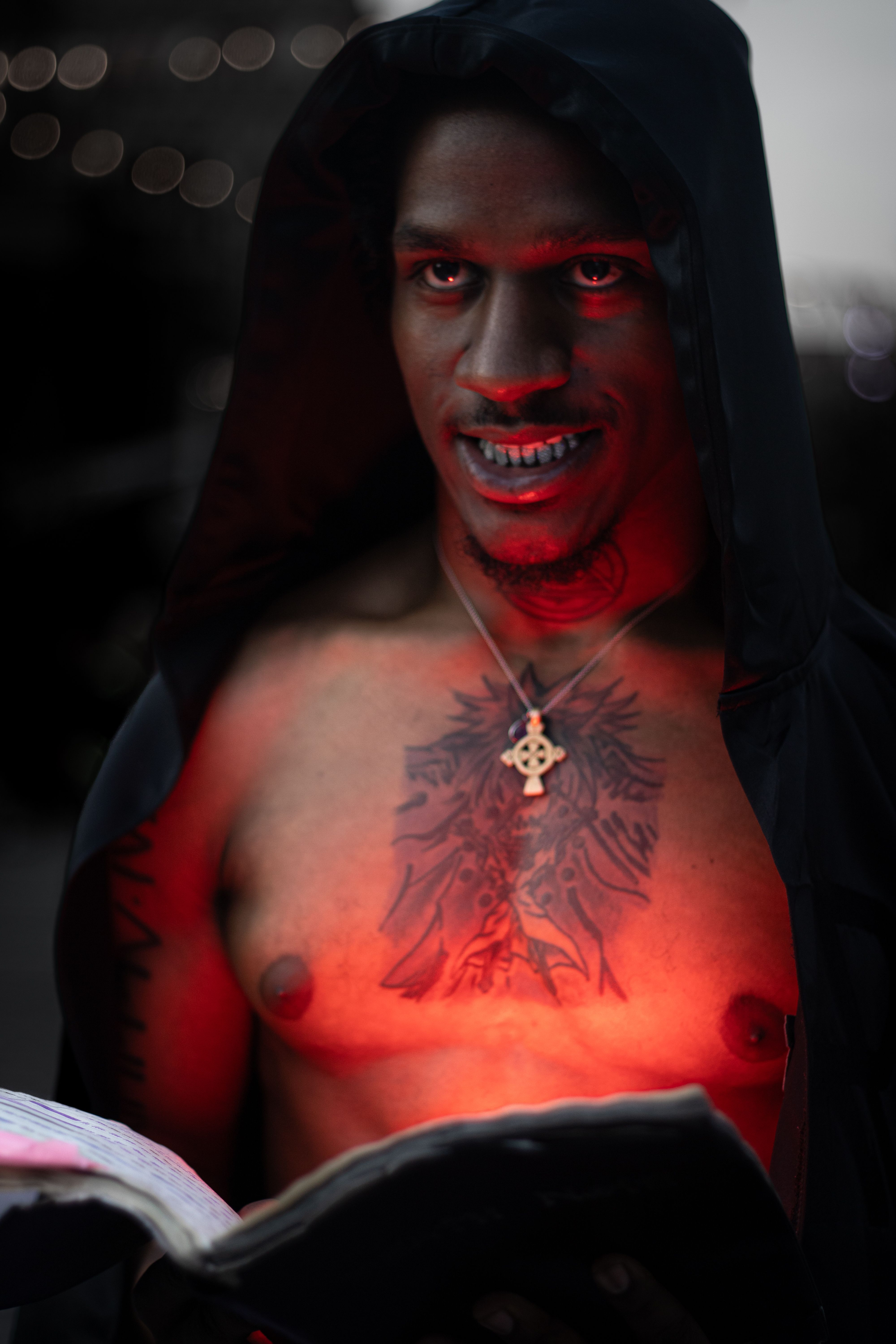 Moody portrait of a hooded man with tattoos and intense lighting, creating a mysterious atmosphere.