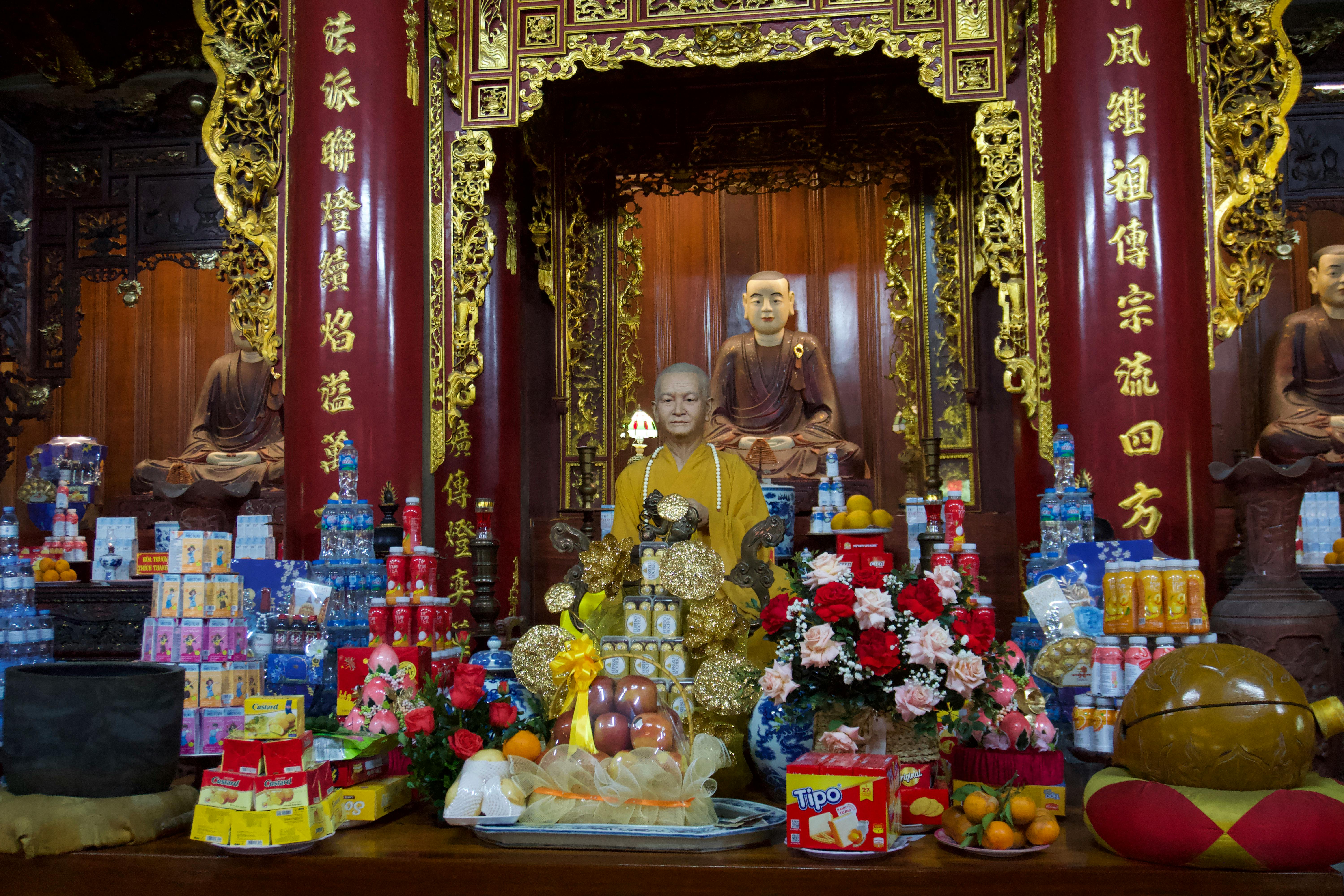 Buddhist statues adorned with offerings at Nom Pagoda, Hung Yen, Vietnam, showcasing traditional spiritual practices.