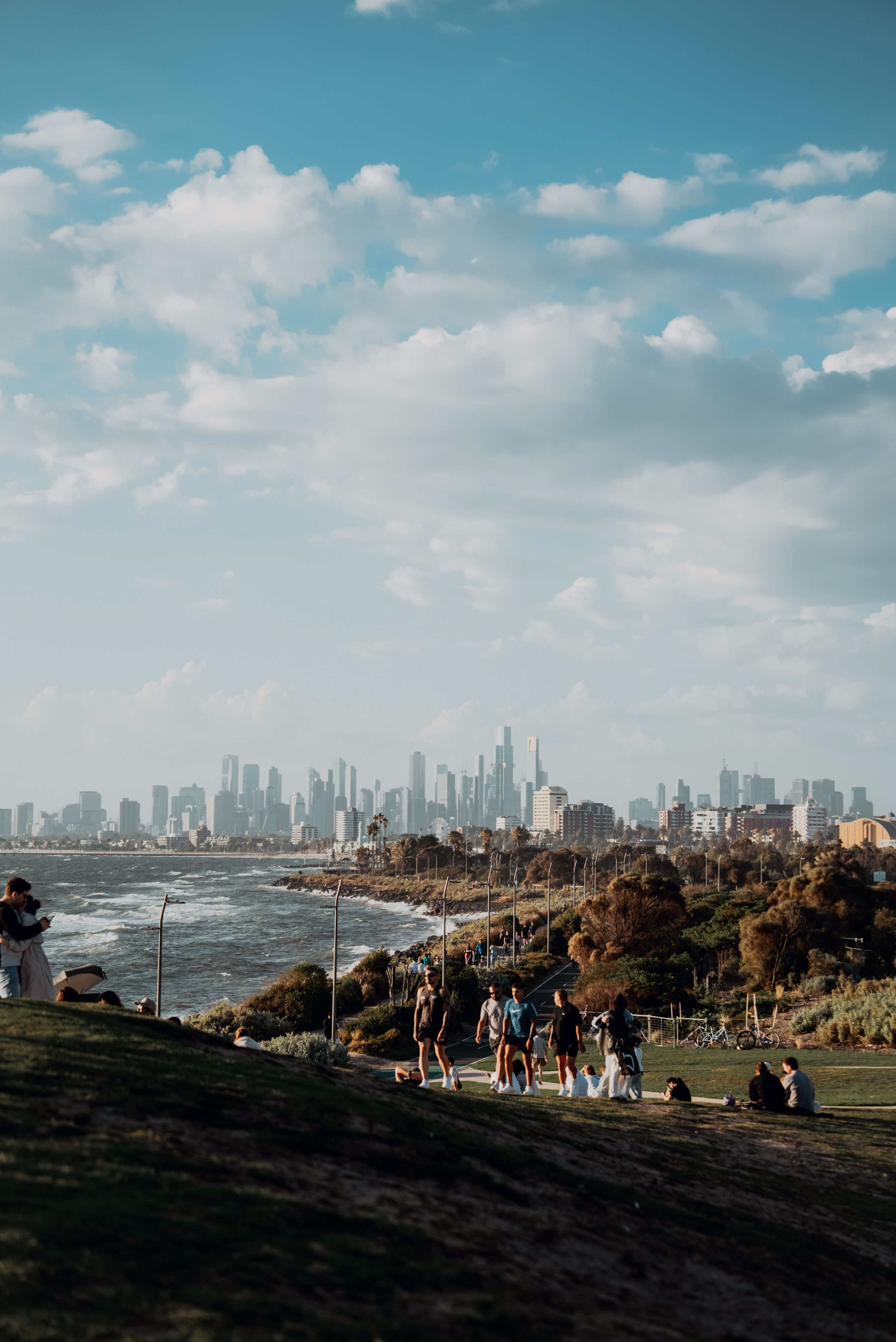 People walking beside the bay with the Melbourne skyline in the distance