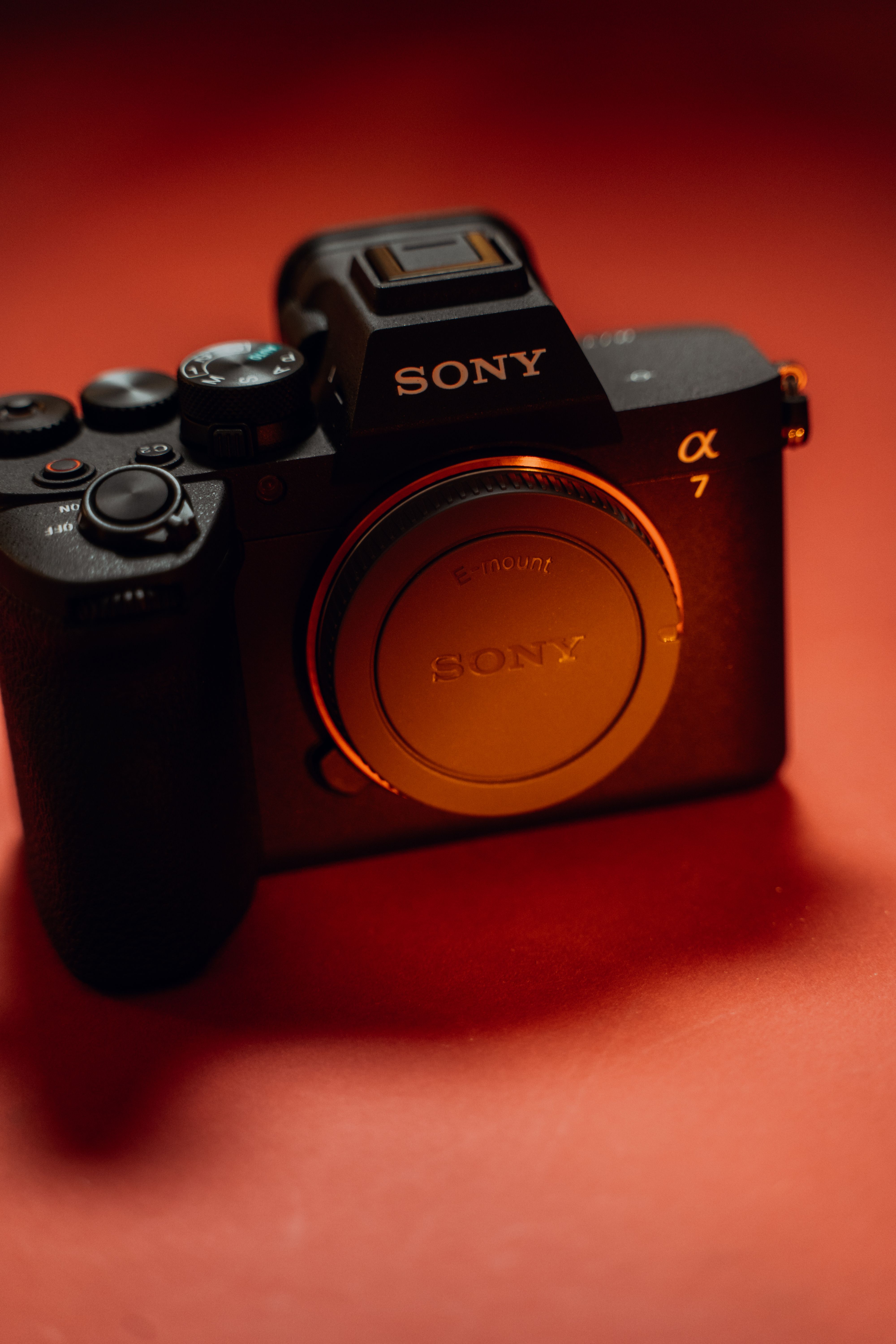 Close-up of a Sony mirrorless camera on a vibrant red background. Perfect for photography and tech-focused projects.