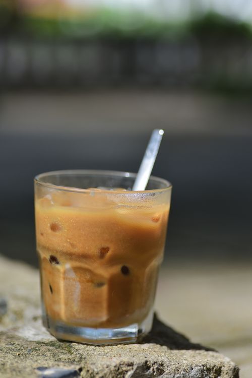 Free A refreshing glass of iced coffee with spoon on a stone surface, perfect for a sunny day. Stock Photo