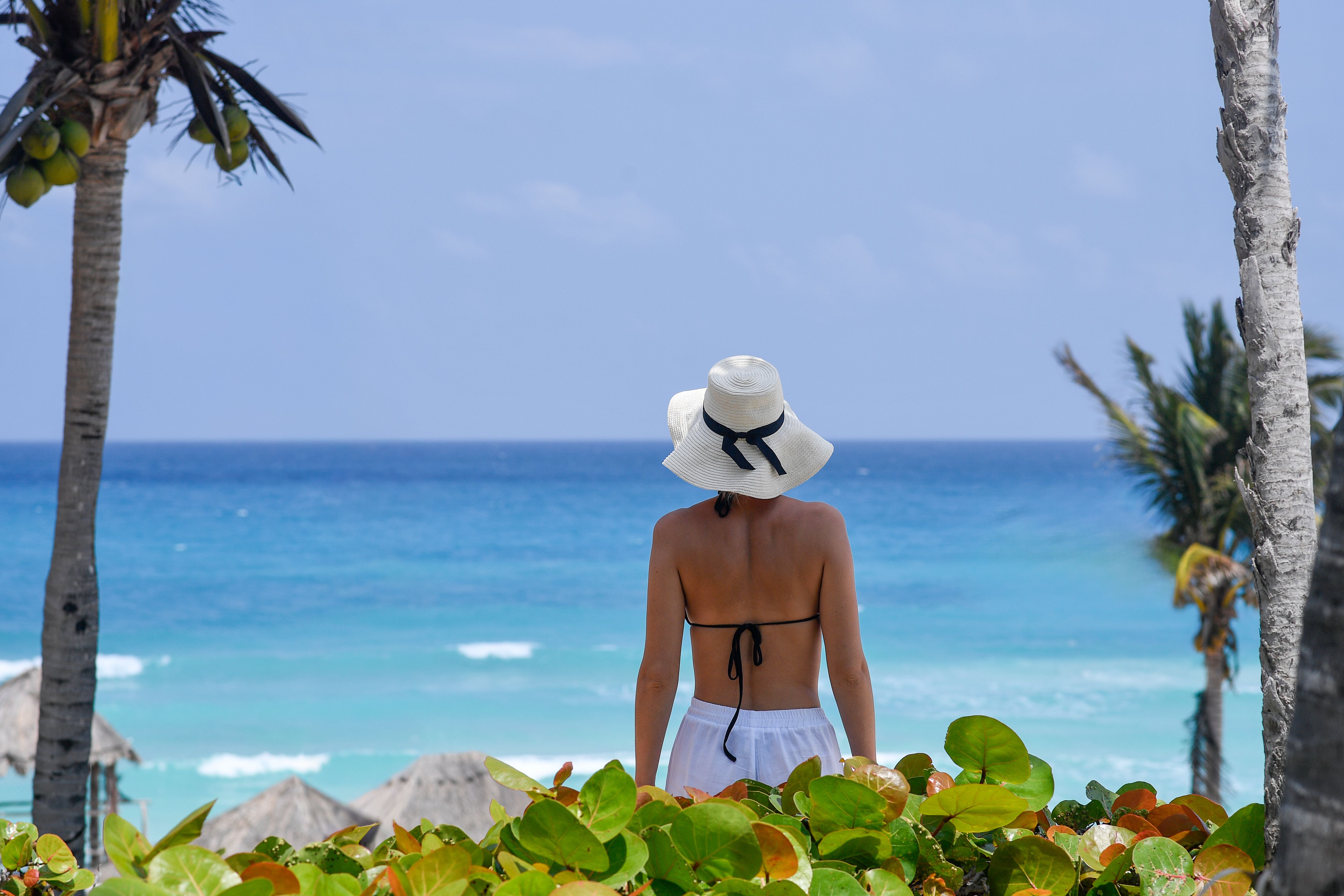 Back view of a woman with sun hat looking at the ocean in Cancún, Mexico.