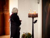 Senior woman lights candles in a peaceful Polish church interior, capturing a moment of reflection.