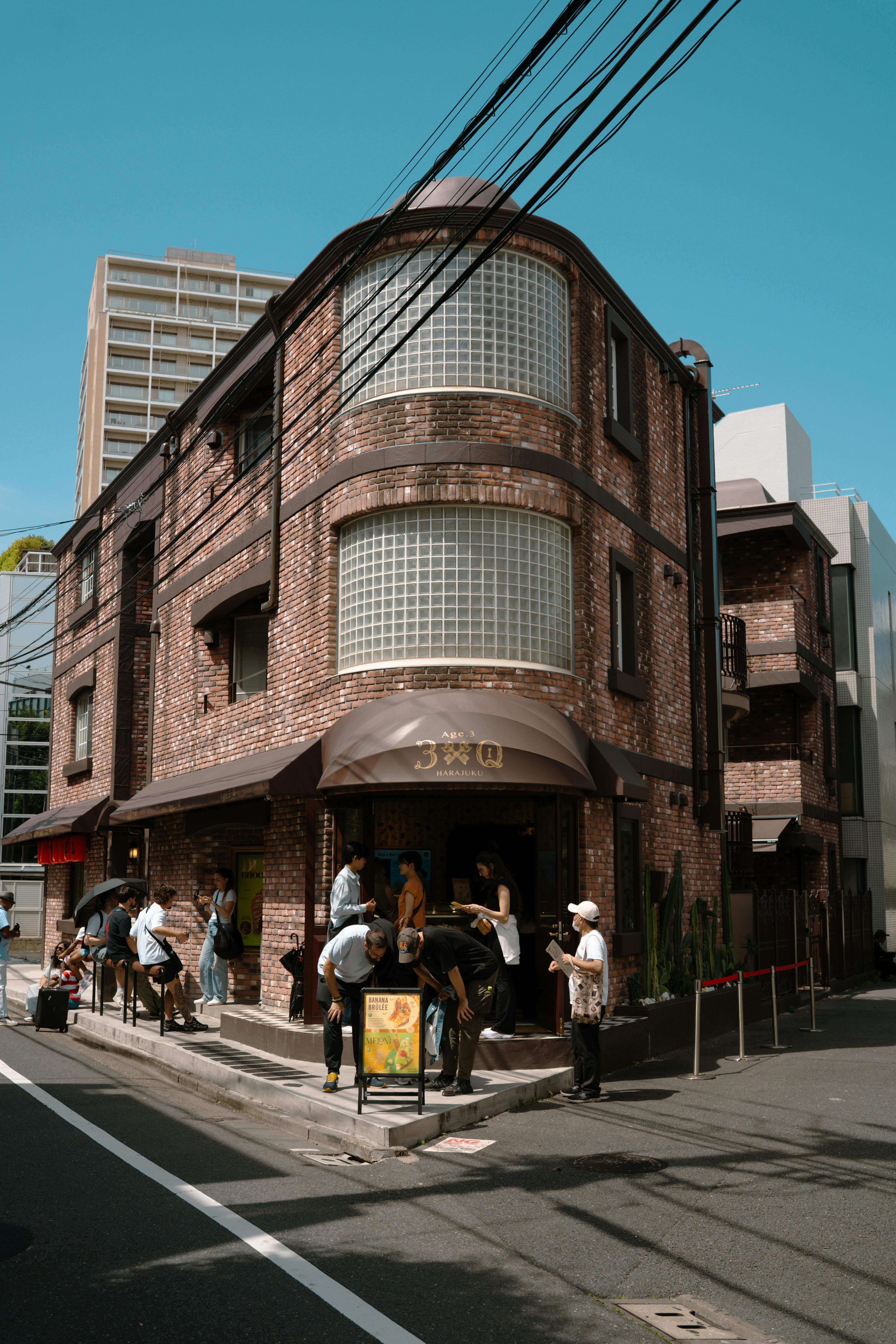 People gather on a sunny street corner in Tokyo, Japan, showcasing unique brick architecture.