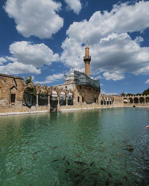 Free A serene view of a historic mosque with a reflective pool and cloudy sky, capturing tranquility and architectural beauty. Stock Photo