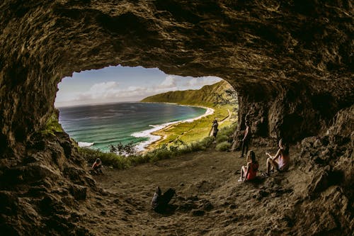 Free People Sitting Inside a Cave Near Body of Water Stock Photo