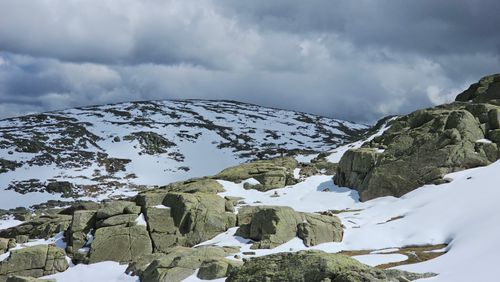 Free Snow-covered mountain terrain in Castile and León, Spain, emphasizing rugged rock formations and overcast skies. Stock Photo