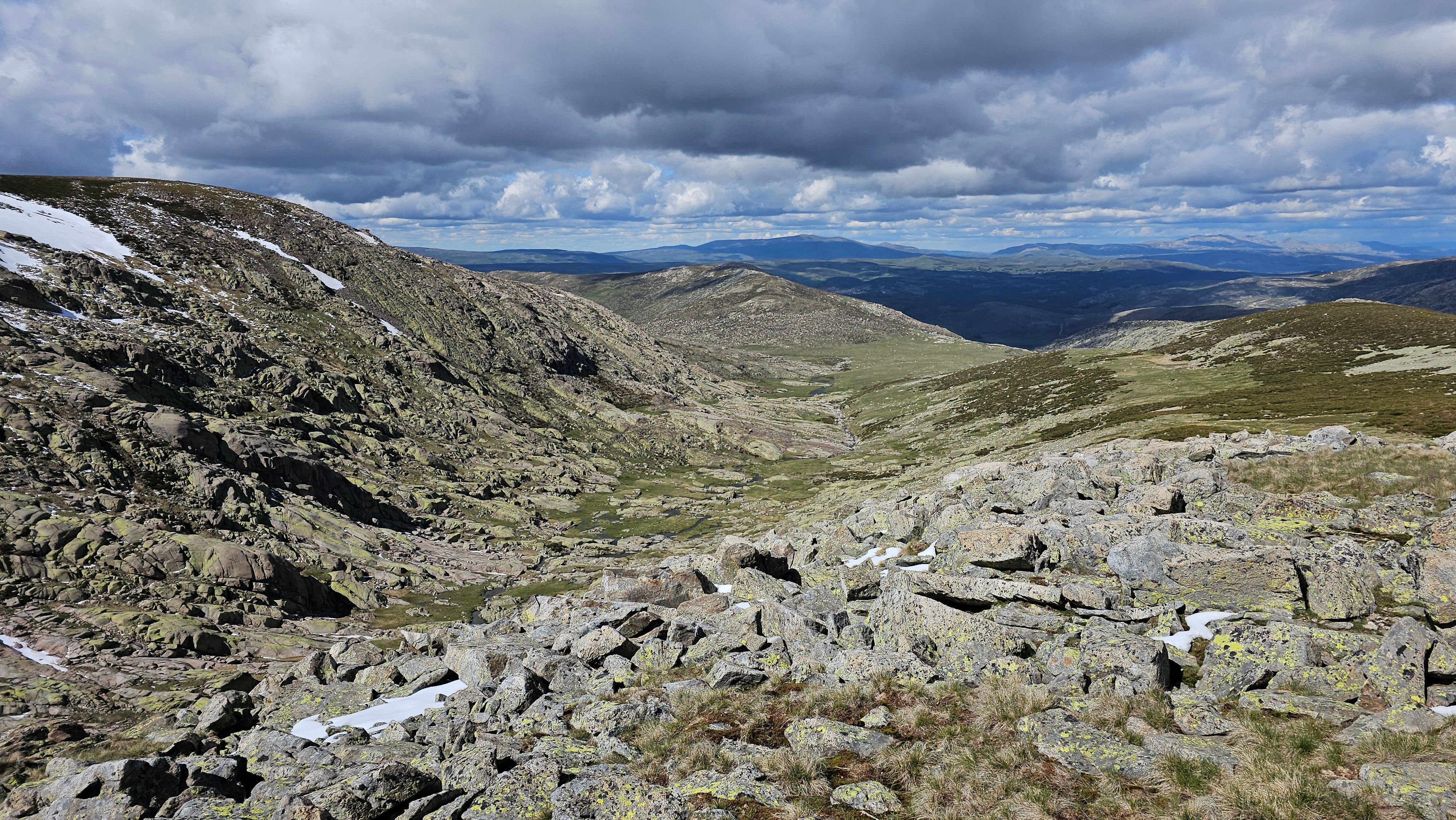 A breathtaking view of rocky mountains and valleys under a dramatic sky.