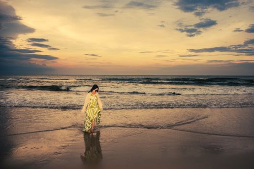 Free A woman strolls along Cửa Tùng beach at sunset, enjoying tranquil ocean views and warm hues. Stock Photo