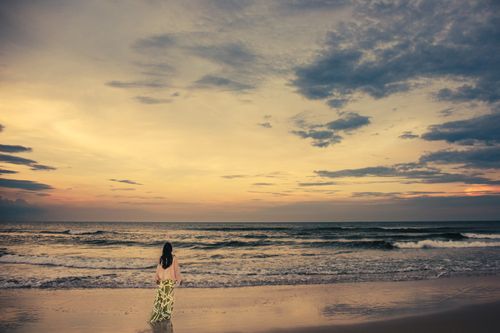 Free A serene moment captured as a woman strolls along Cửa Tùng Beach during sunset. Stock Photo