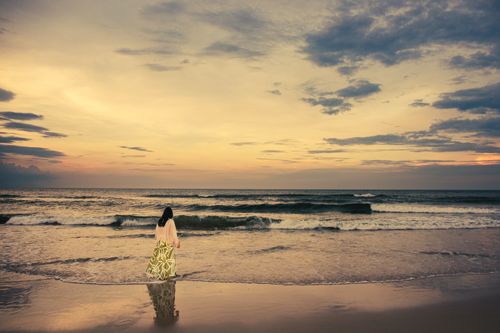 Free A woman stands by the serene beach of Cửa Tùng, Vietnam at sunset, embracing tranquility. Stock Photo