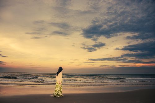 Free A woman stands alone at sunset on Cửa Tùng Beach, Quảng Trị, Vietnam. Captivating serene moment. Stock Photo