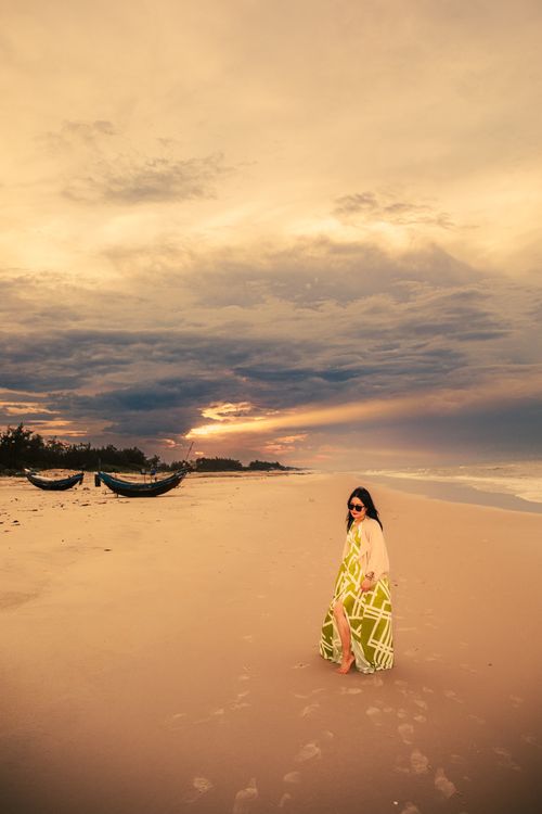Free A woman enjoys a peaceful walk along Cửa Tùng Beach in Vietnam during a picturesque sunset. Stock Photo