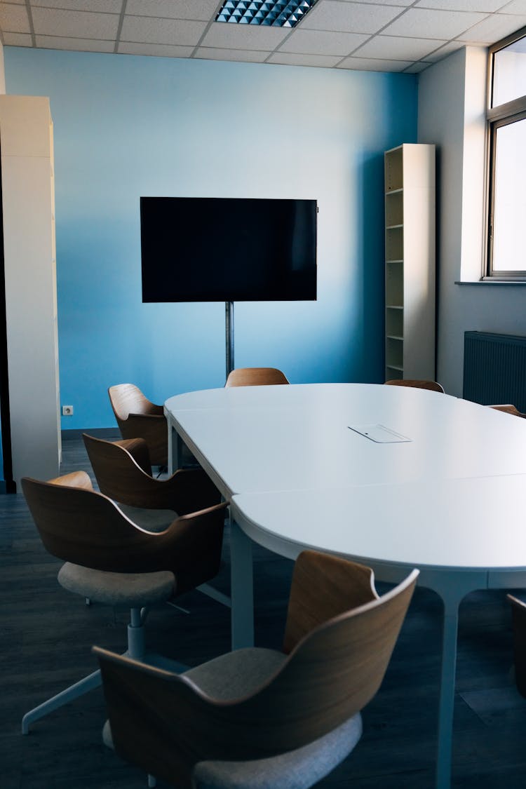 Interior Of Modern Office With Oval Table And Chairs Against TV