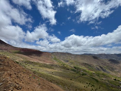 Free Breathtaking view of the Atlas Mountains with vibrant greenery under a stunning blue sky and fluffy clouds. Stock Photo