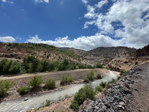 Free A picturesque view of a river flowing through a valley in the Atlas Mountains, under a bright blue sky. Stock Photo