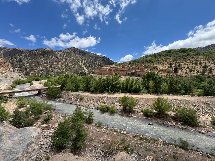 Beautiful mountain landscape with a river and traditional village under a clear blue sky.