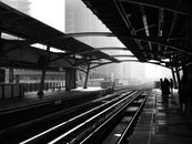 Silhouettes of anonymous people standing on railway platform