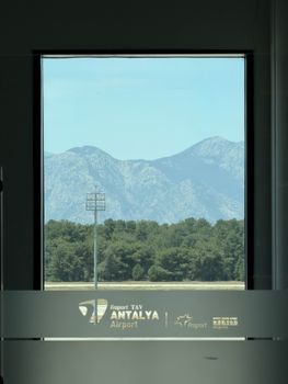 A serene view of the Taurus Mountains through a window at Antalya Airport, Turkey.