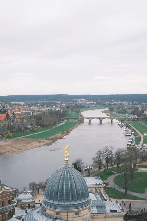 Free A beautiful aerial view of Dresden, Germany featuring the Elbe River and historical architecture under a cloudy sky. Stock Photo