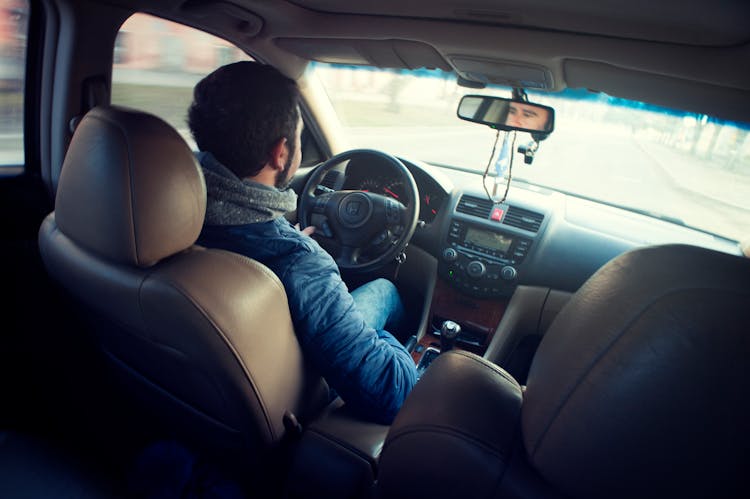 Man Wearing Blue Jacket Sitting Inside Car While Driving