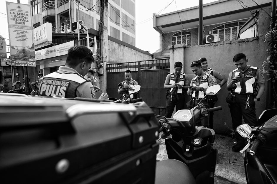 A group of police officers gather around motorcycles in a city street.