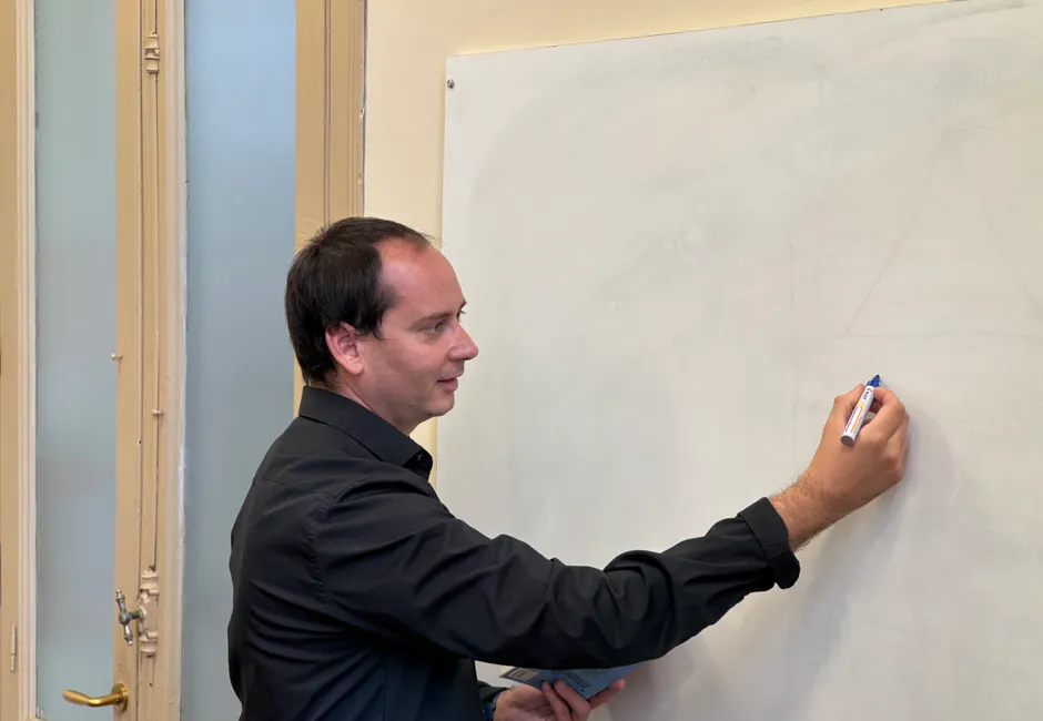 Formateur écrivant au feutre sur un tableau blanc devant une salle de formation