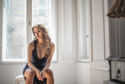 Photo of Woman in a Black Sleeveless Dress Sitting on the Floor While ...
