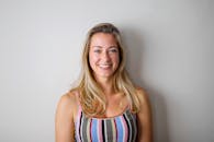 金发女子穿着条纹背心，白色背景下微笑，散发着幸福感