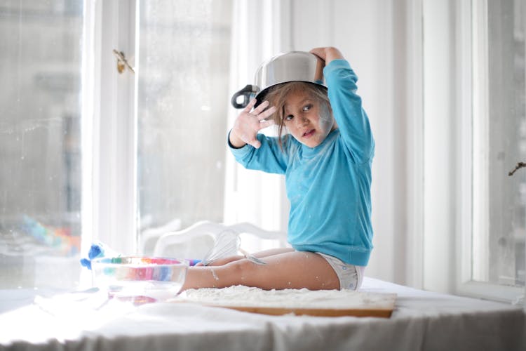 Little Girl Playing With Pan And Flour In Kitchen