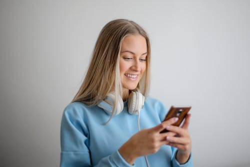 Free Woman in Blue Long Sleeve Shirt Holding Brown Smartphone Stock Photo